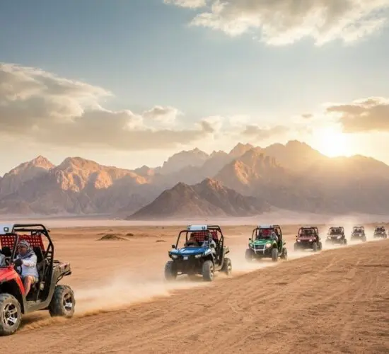 Convoy of 2-seater buggies racing through Sharm El Sheikh's Sinai desert at dusk, kicking up dust with dramatic red rock mountains and hazy skies