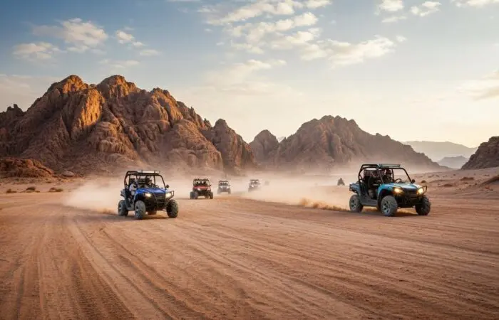 Double-seater buggy kicking up sand while racing across Sharm El Sheikh's desert at sunset, Sinai mountains glowing behind