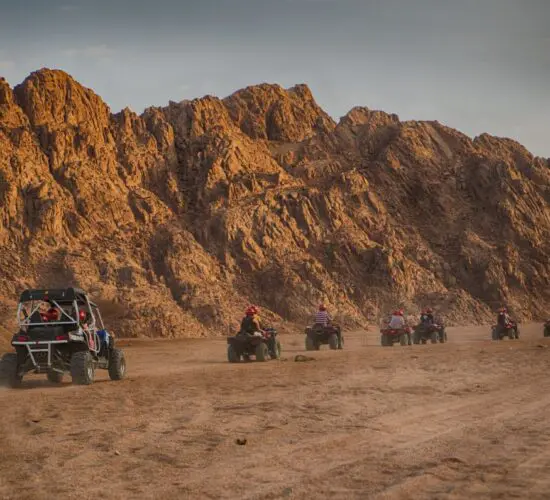 Adrenaline-packed quad bike ride tearing across Sharm El Sheikh's golden desert dunes with rugged Sinai mountains behind.