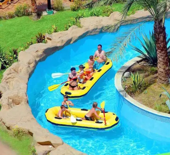 Adventurous guests racing down the bright orange and yellow twisting water slides at Sharm El Sheikh’s aqua park, splashing into the pool under sunny skies.