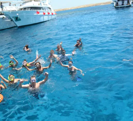 Boat snorkeling trip at Ras Mohammed: guests in clear turquoise waters surrounded by vibrant coral reefs and schools of fish, Sharm El Sheikh.