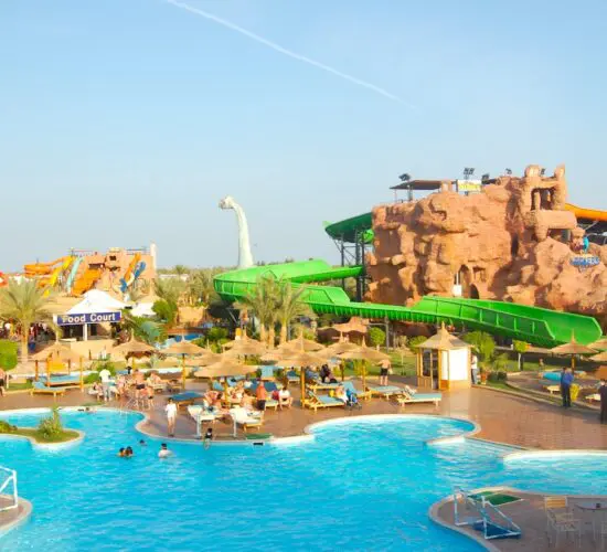 Exciting water park in Sharm El Sheikh with massive colourful slides, lazy river pools and palm trees attractions under sunny skies.